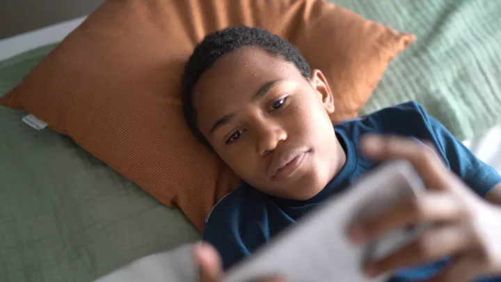 Boy on pillow with phone.