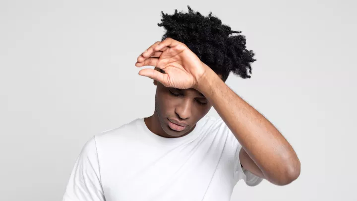 Teenager touching his forehead.