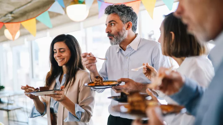 Man eating cake with his colleagues at a party