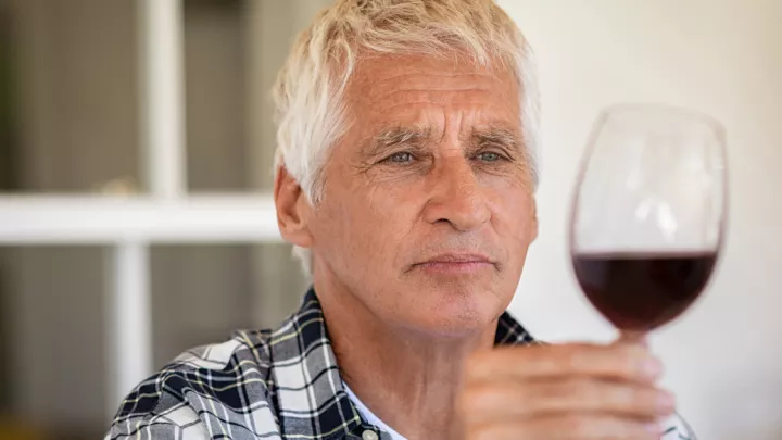 Older man holding a glass of red wine