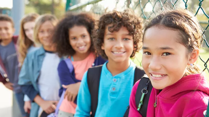 Line of young girls standing against a chain link fence