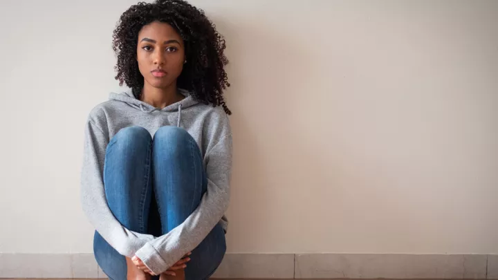 A woman sitting near a wall