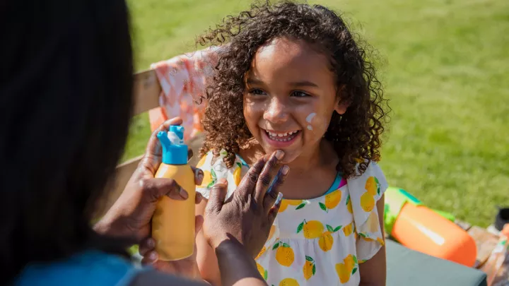 A mother putting sunscreen on a young girl