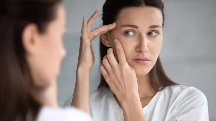 picture of a woman looking at her skin in the mirror