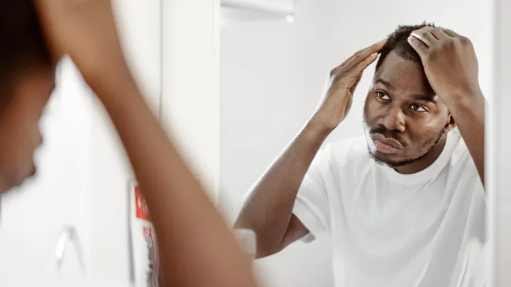 A man looking through his hair in the mirror