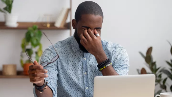 Man sitting in front of his computer rubbing his eyes