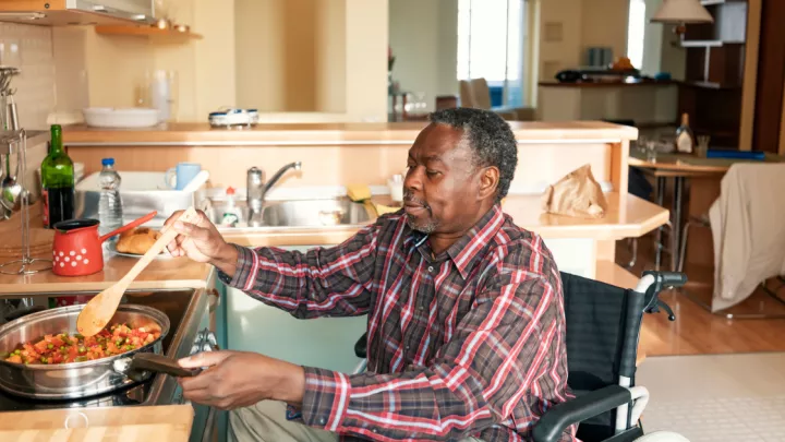 Older man in a wheelchair making food on the stove