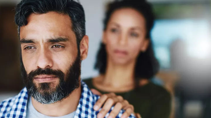 Man with woman's hand on his shoulder