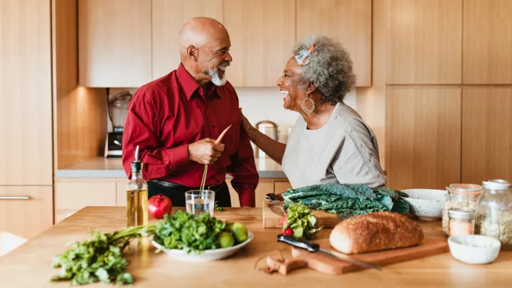 An older couple standing in the kitchen preparing a meal