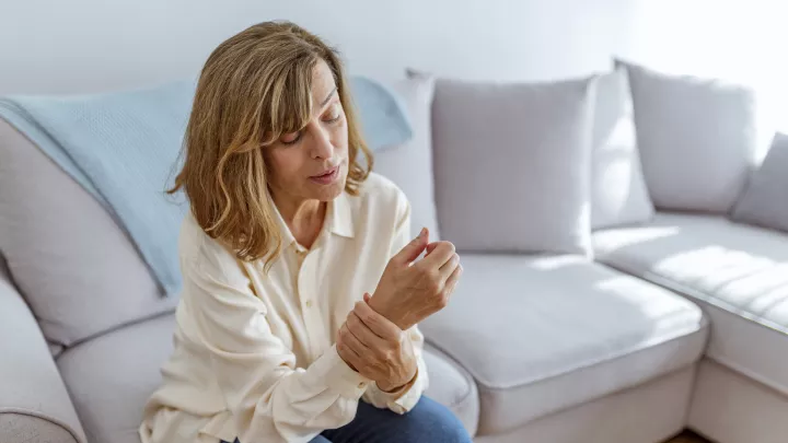 Woman sitting on the couch holding her wrist