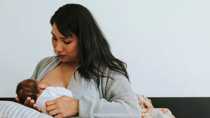 Woman breastfeeding sitting in her bed