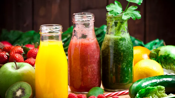 Three juice bottles surrounded by fruit