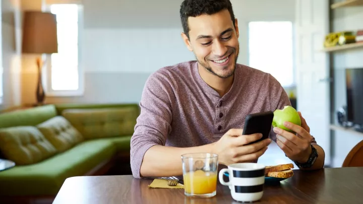 Man eating apple while looking at phone