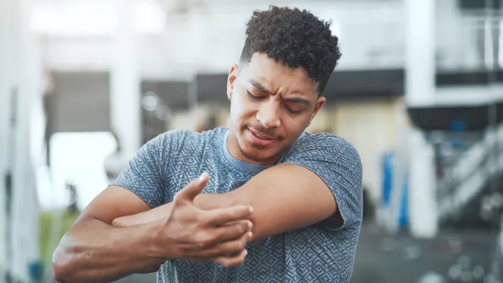 Man at the gym grabbing his elbow