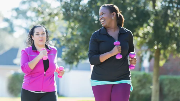 Two women running holding weights